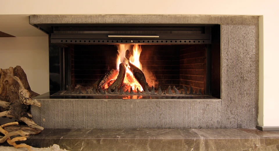 Cheminée moderne encastrée dans mur intérieur avec feu de bois actif, flammes vives et bûches consumées