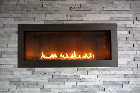 Int&eacute;rieur r&eacute;sidentiel avec chemin&eacute;e en briques rouges &eacute;quip&eacute;e d'un insert de chauffage au bois